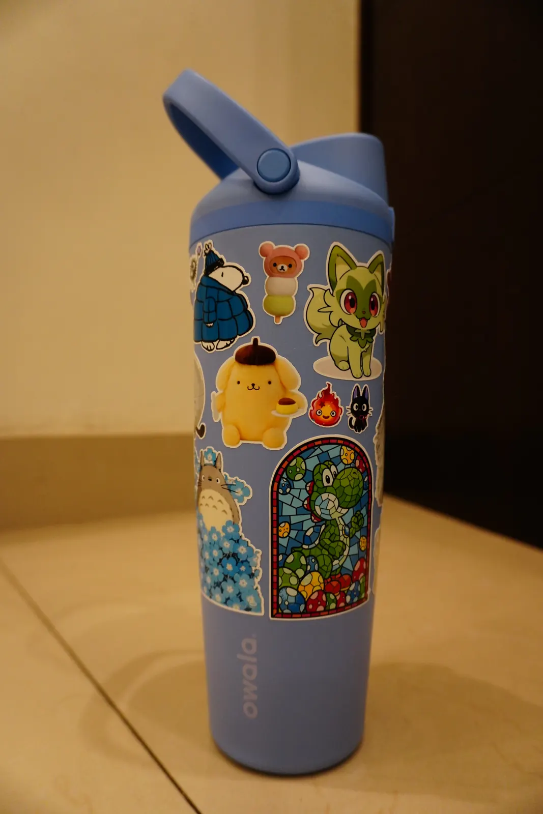 Termo azul cubierto de stickers de vinil troquelados: Snoopy, Pompompurin, Sprigatito, Totoro, Calcifer, Jiji y Yoshi de vitral