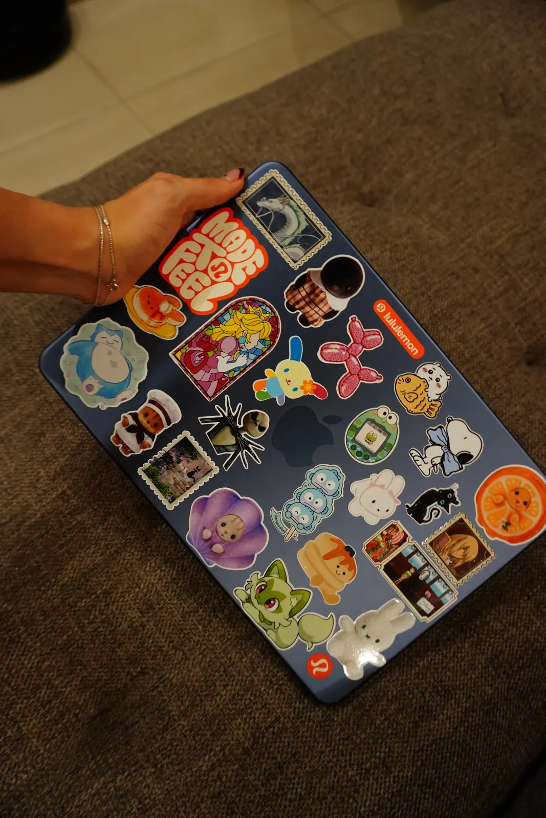 Laptop azul cubierta de stickers de vinil: Snorlax, Jack Skellington, Hangyodon, Miffy, Sprigatito y estampillas de Studio Ghibli